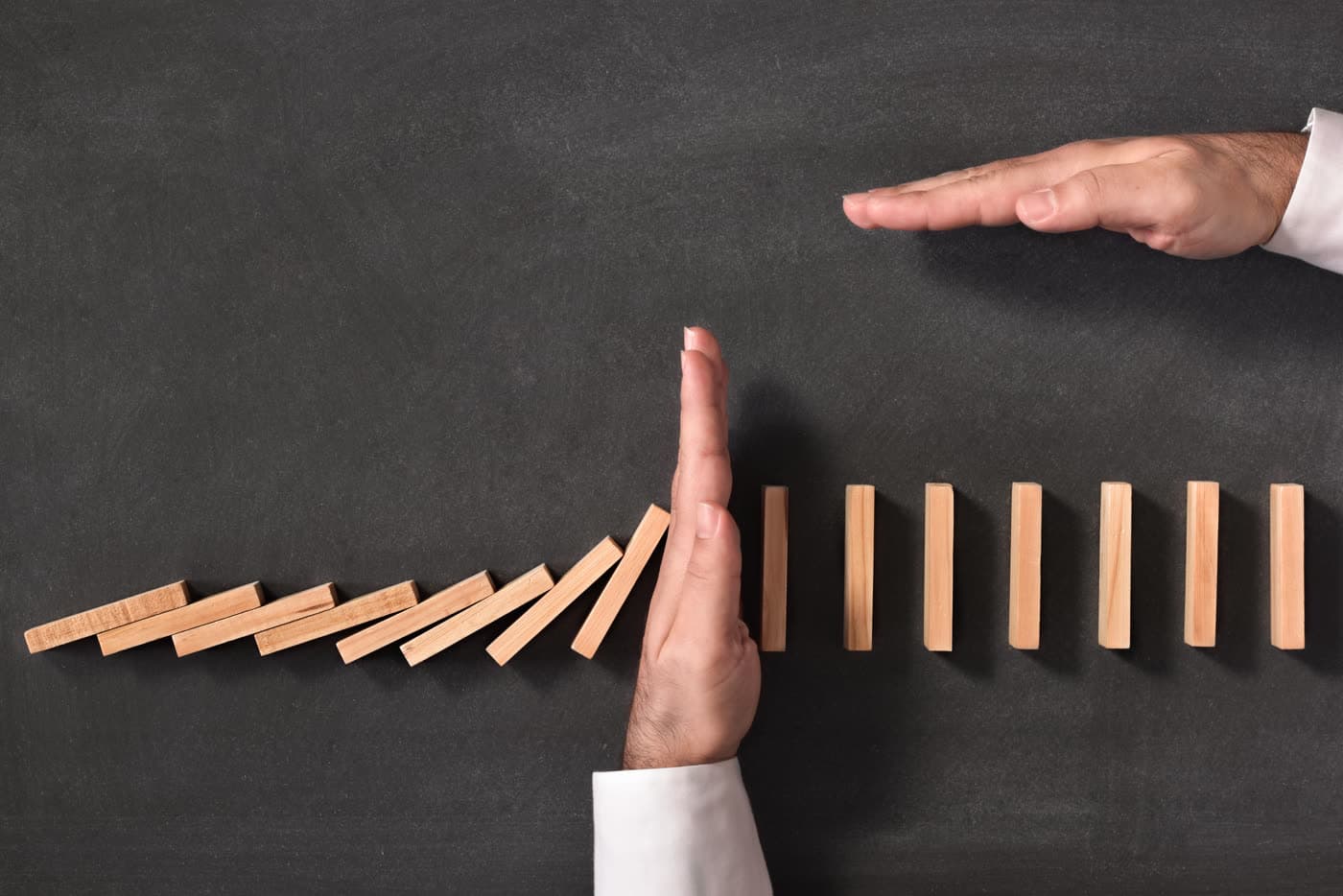 Hand stopping falling dominos — protecting your operations